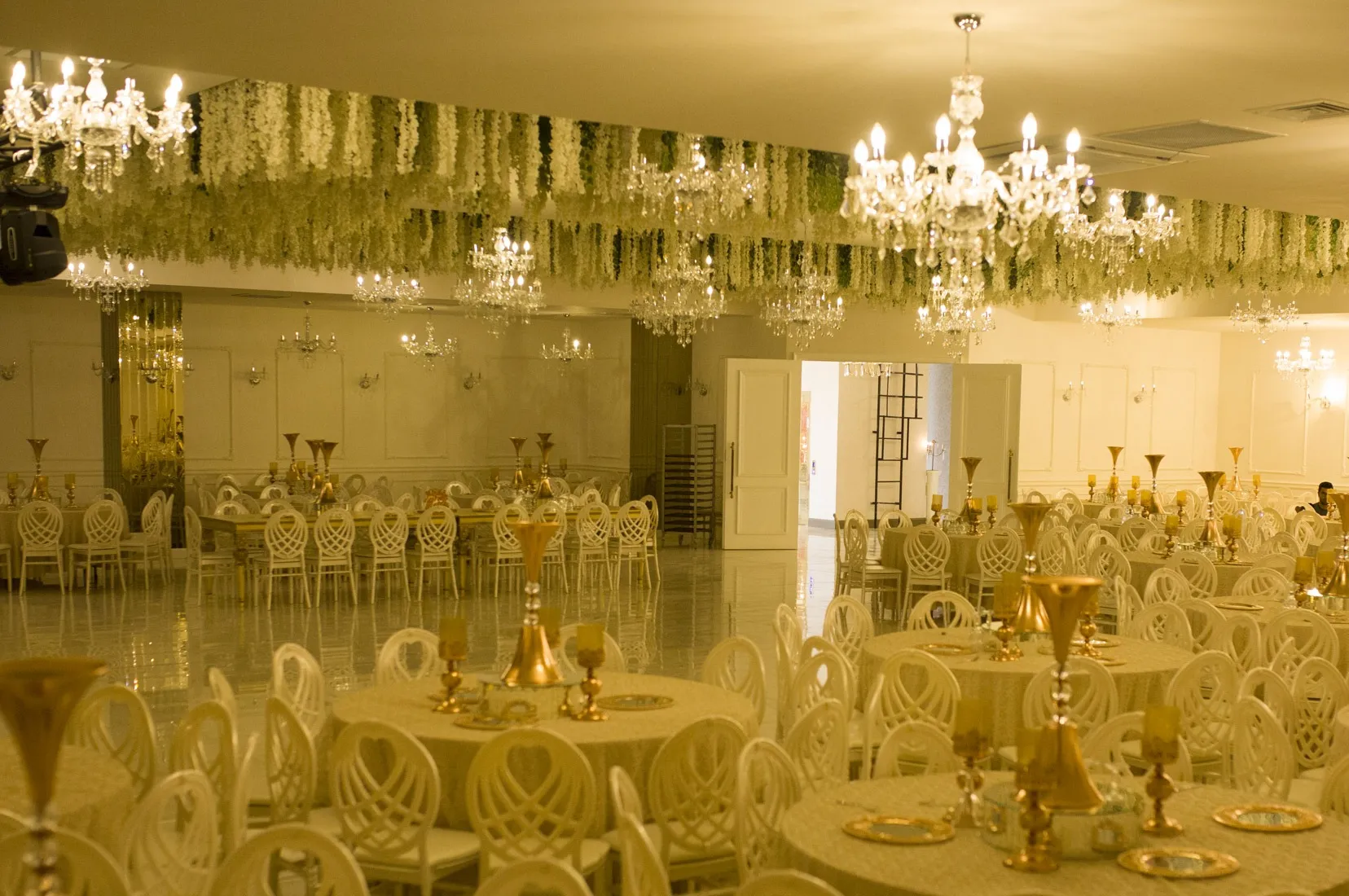 Boutique Salon'da tavandan sarkan çiçek düzenlemesi ve hazırlanmış masalar